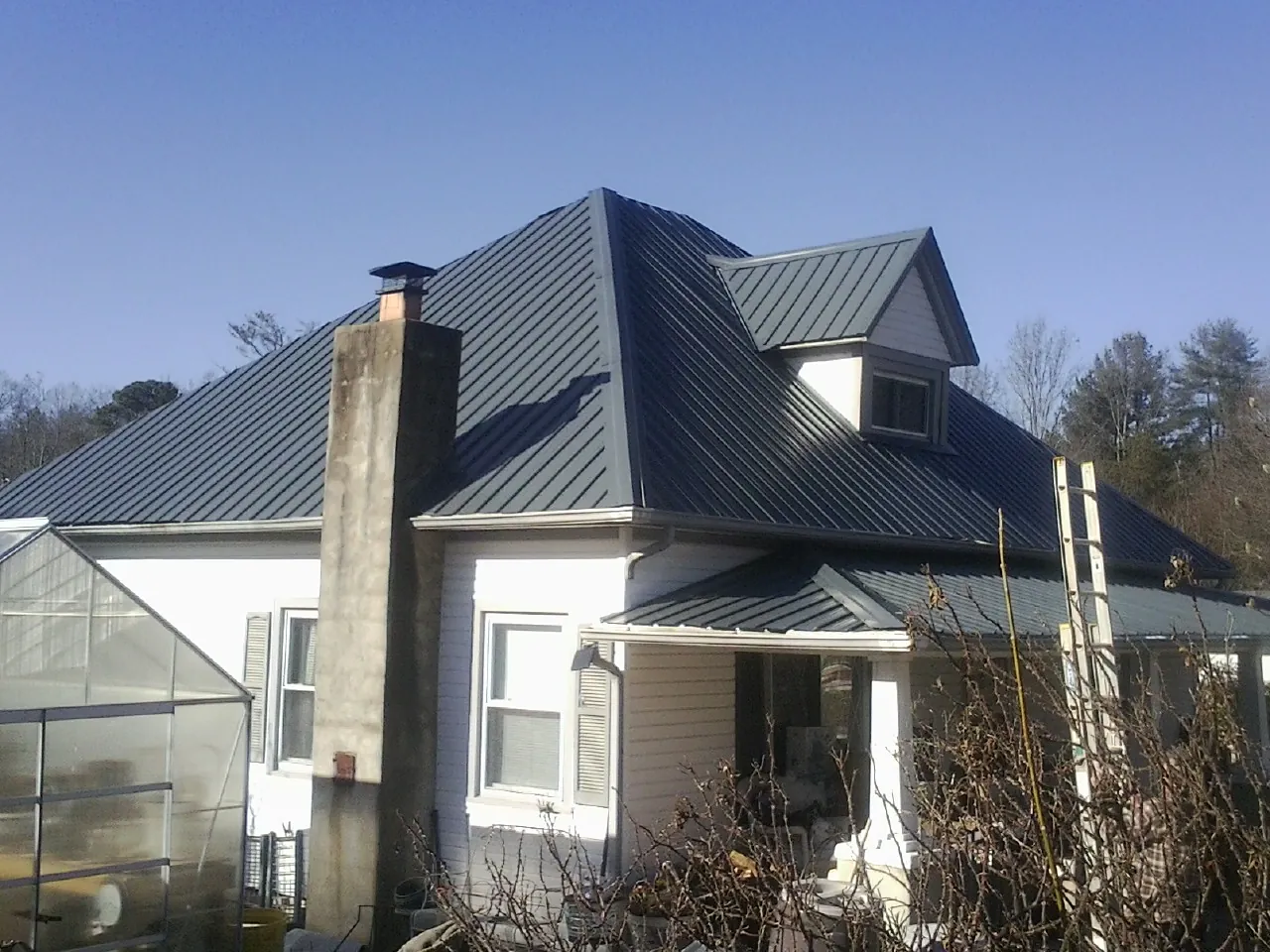 Dark blue standing seam metal roof on a white farmhouse with dormer — Slate & Tile Roof Repair by Roofing Brothers in Ball Ground