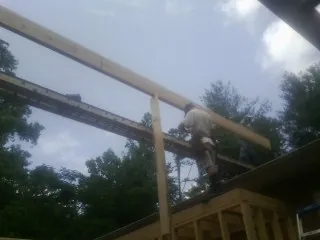 Carpenter setting a ridge beam over a new addition frame — Ice Dam Removal by Roofing Brothers in Ball Ground