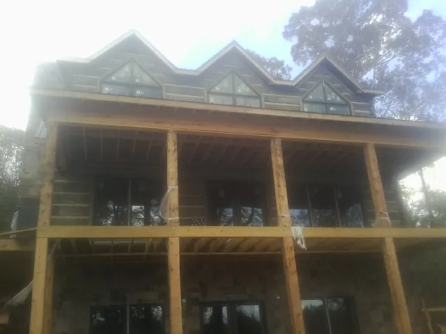 Dormers and porch framing on a large log home under construction — Roof Coating work by our crew in Ball Ground