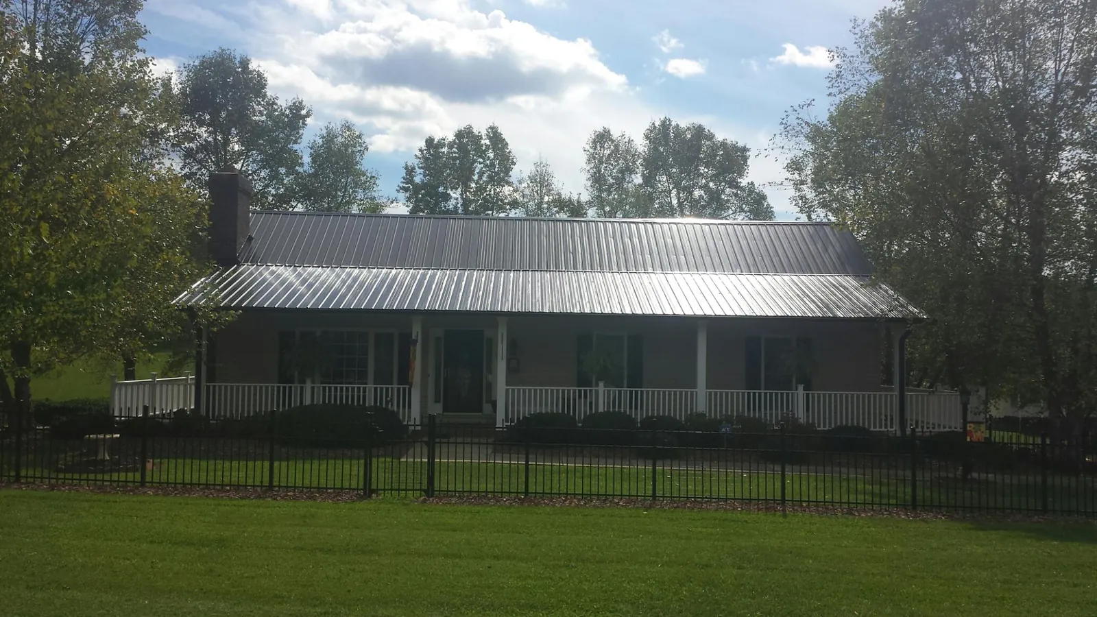 Gray metal roof on a brick ranch with a full width front porch — Gutter Guard Installation work by our crew in Ball Ground