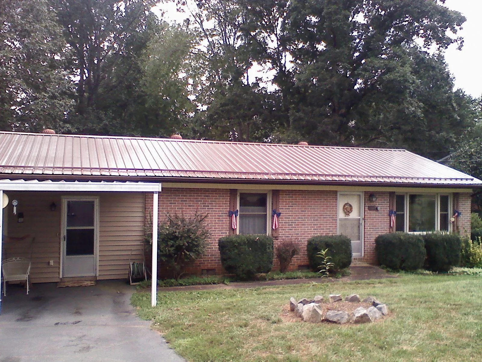 Bronze metal roof and carport on a brick ranch home — Roof Repair work by our crew in Ball Ground